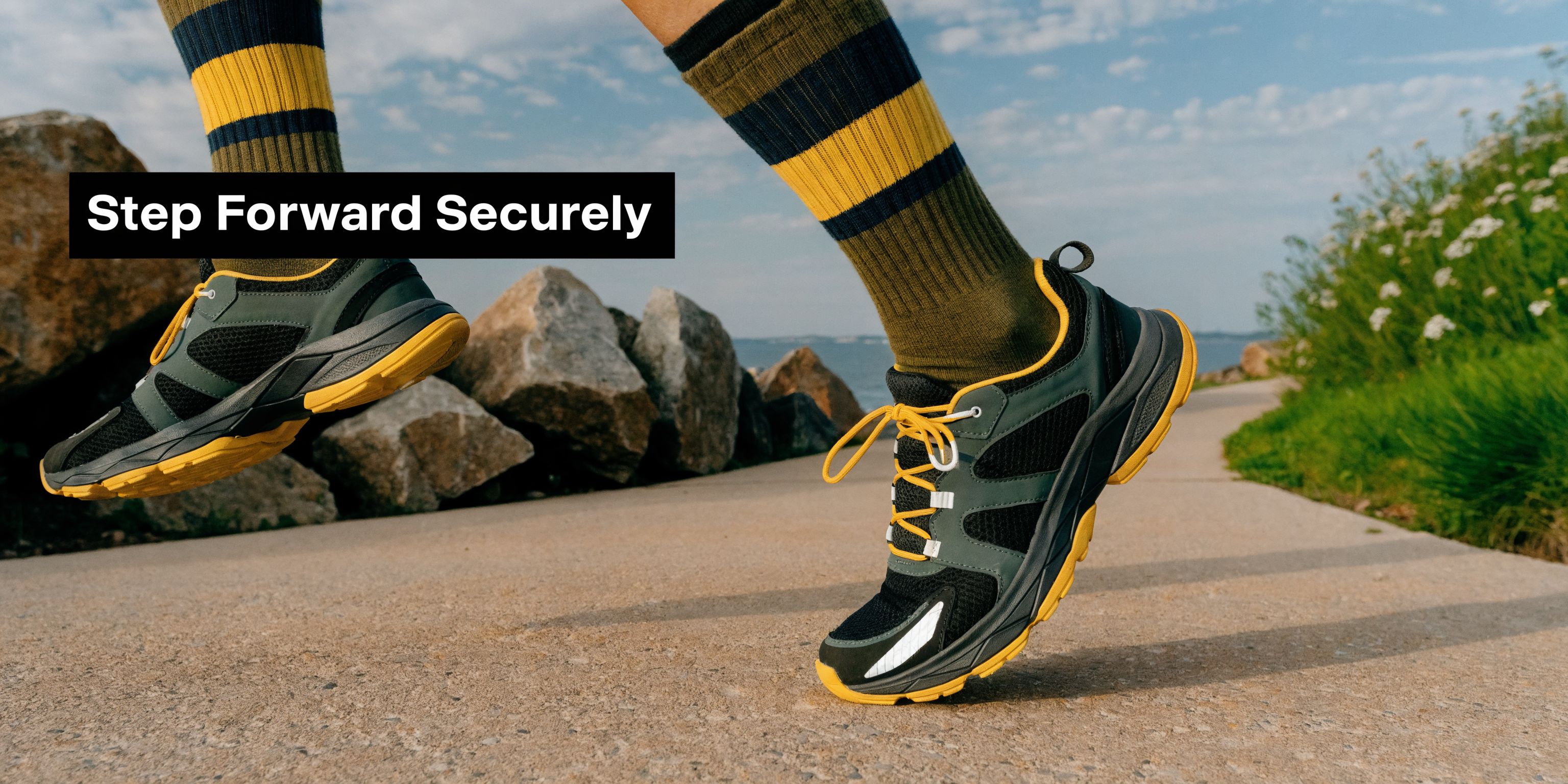 A person running on a concrete path wearing dark green and yellow sneakers and matching striped socks.