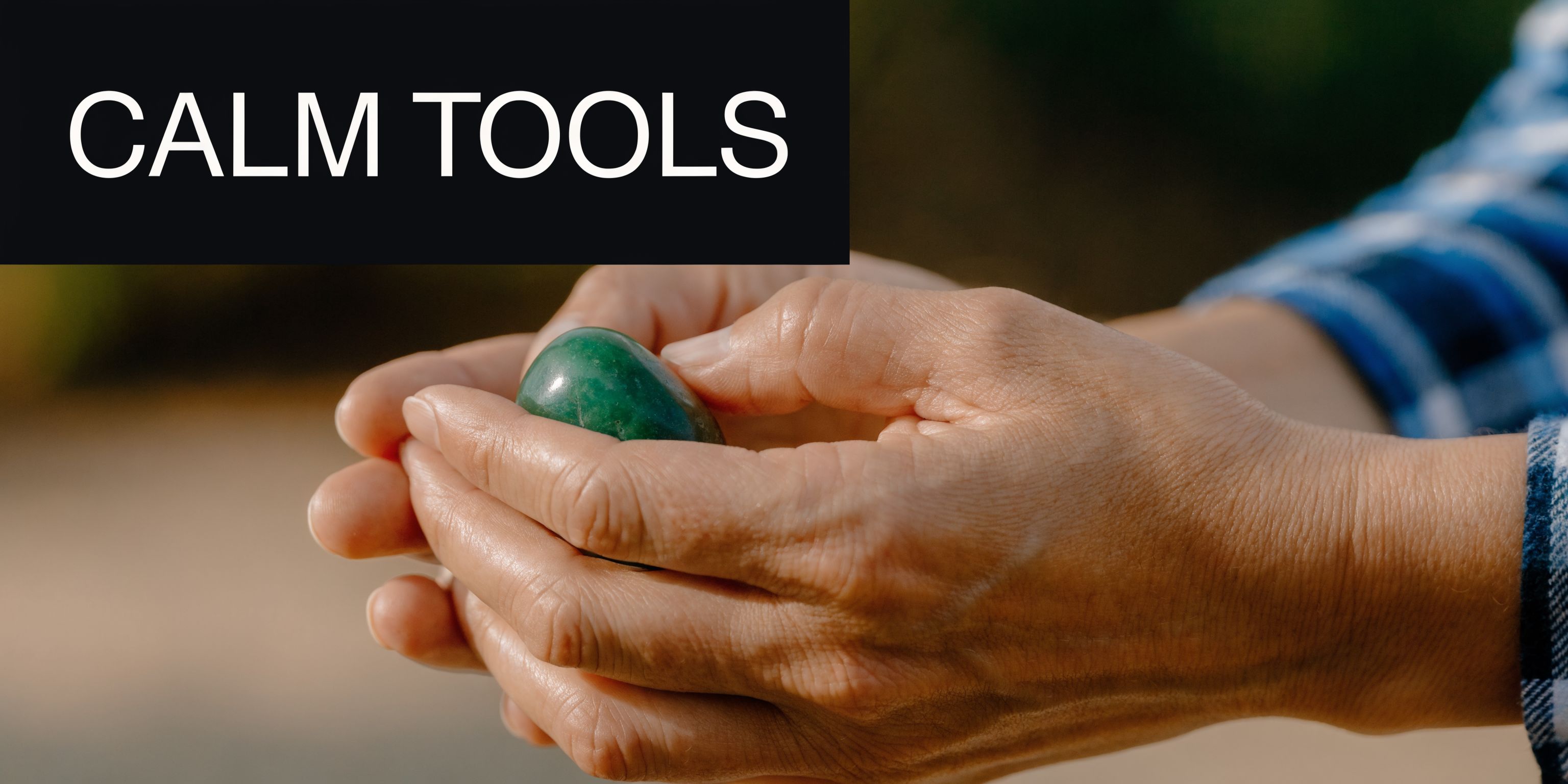 A person holding a smooth green crystal stone in their cupped hands as a calming grounding tool.