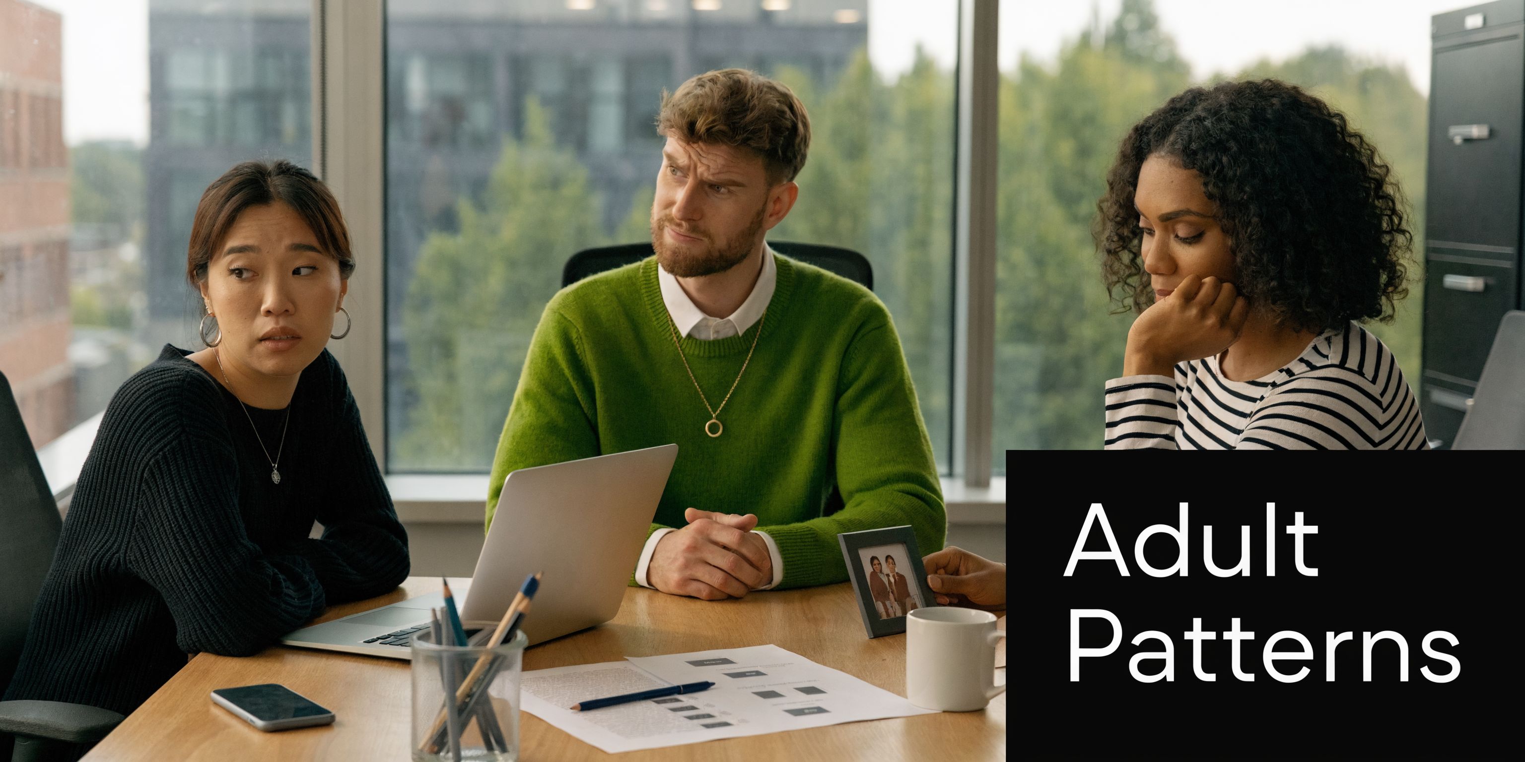 Three colleagues sitting at an office table looking stressed and uncomfortable during a collaborative work meeting.